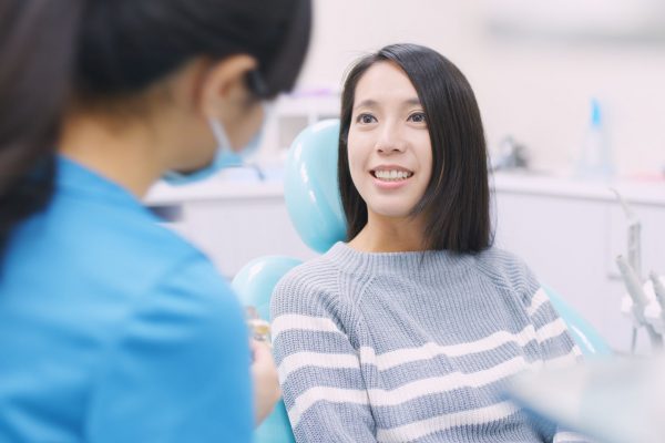 woman speaking to a dentist while sitting in a dental chair
